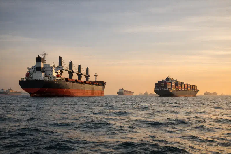 Dense rows of bulk carriers and container vessels at anchor in ASEAN waters, waiting for berth allocation during peak Q3 shipping season